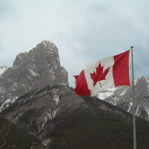 The Canadian flag in front of snow capped mountains.