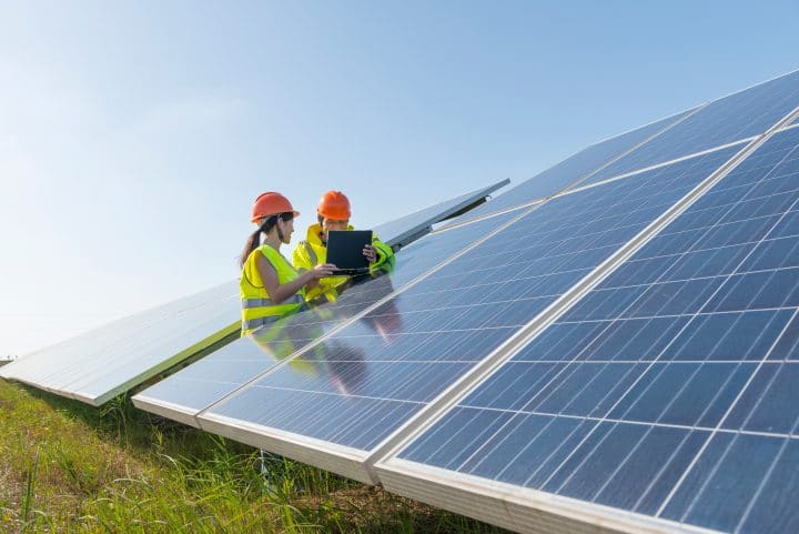 Two renewable energy workers inspecting a solar panel.